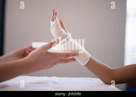 Nahaufnahme des weiblichen Therapeuten Umhüllung Verband einerseits auf Krankenstation Stockfoto