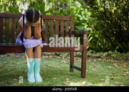 Deprimiert Mädchen sitzen auf Holzbank mit Kopf in Händen im Hinterhof Stockfoto