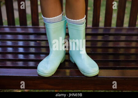 Geringen Teil der Mädchen trägt grüne Gummistiefel stehen auf Holzbank im Hinterhof Stockfoto