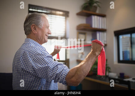 Seitenansicht des senior Man zieht Widerstand Band stehend in Spitalabteilung Stockfoto