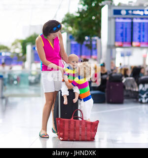 Familie am Flughafen vor dem Flug. Mutter und Kinder an Bord am Abflug-Gate des modernen internationalen Terminals warten. Reisen und fliegen mit childr Stockfoto