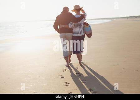 Älteres Paar zu umarmen und zu Fuß am Sonnenstrand Stockfoto