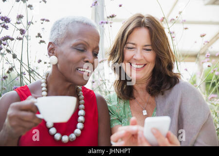 Lächelnde Reife Frauen Freunden Kaffee trinken und mit Handy Stockfoto