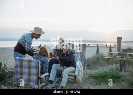 Ältere Ehepaare, Grillen, trinken Wein am sunset beach Stockfoto