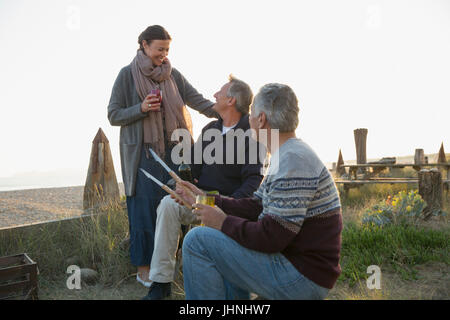Ältere Freunde grillen und Weintrinken am sunset beach Stockfoto