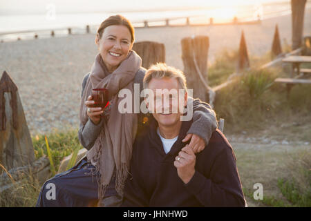 Porträt, Lächeln älteres paar Hand in Hand und Weintrinken am sunset beach Stockfoto