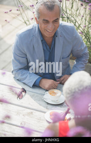 Älteres paar reden und Kaffeetrinken am sonnigen Patio Tisch Stockfoto