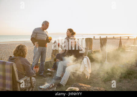 Ältere Ehepaare, Wein trinken und Grillen am Sonnenuntergang Strand Stockfoto