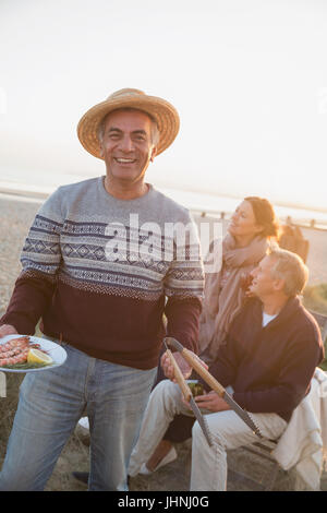 Porträt, Lächeln senior woman Grillen mit Freunden am sunset beach Stockfoto