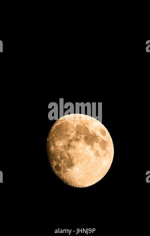 Vertikale Foto schön golden Moon mit sichtbaren Krater am Rande der Schatten. Der Mond ist fast voll mit nur kleinen Teil versteckt in der Dunkelheit. Die li Stockfoto