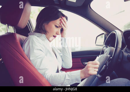 Betonte verzweifelten Frau Treiber mit Dokumenten in ihrer modernen Auto sitzen Stockfoto