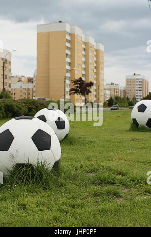 three big soccer balls on the green lawn cityscape Stockfoto
