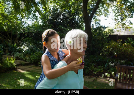 Lächelnde ältere Frau, die die Enkelin hält Blumen im Garten Stockfoto