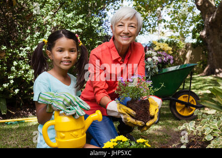 Porträt der lächelnde Mädchen und Großmutter im Garten im Hinterhof Stockfoto