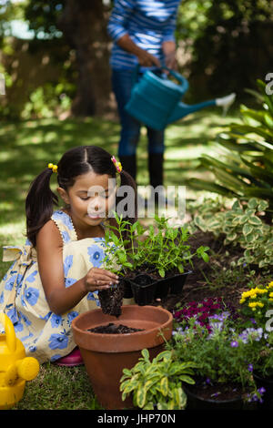 Mädchen, die Pflanzen im Topf während Großmutter Bewässerung von Pflanzen im Garten Stockfoto