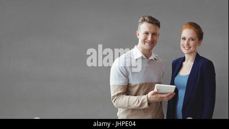 Digital Composite glücklich Geschäftsleute halten eine Tablette vor grauem Hintergrund Stockfoto