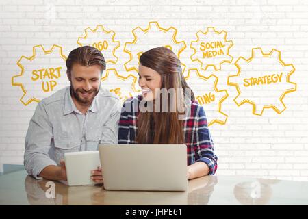 Digital Composite glücklich Geschäftsleute an einem Schreibtisch sah ein Tablet und ein Computer gegen weiße Wand mit gelb gr Stockfoto