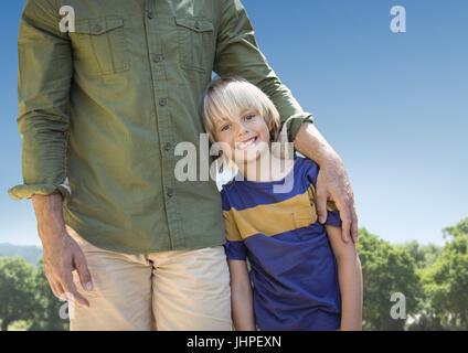 Digitalen Verbund von Vater Arm um Sohn gegen Himmel und verschwommen Bäume Stockfoto