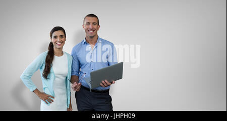 Lächelnde Geschäftsleute mit einem Laptop gegen graue vignette Stockfoto
