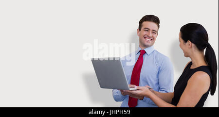 Unternehmer und Unternehmerin halten einen Laptop vor grauem Hintergrund Stockfoto