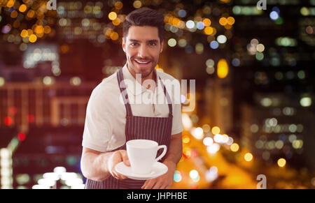 Kellner zeigt eine Tasse Kaffee gegen defokussierten Bild beleuchtete Gebäude Stockfoto