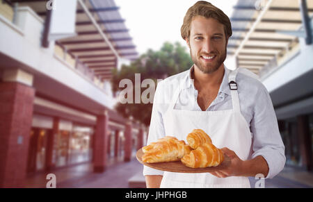 Zusammengesetztes Bild der Kellner halten Croissant auf einem Tablett Stockfoto
