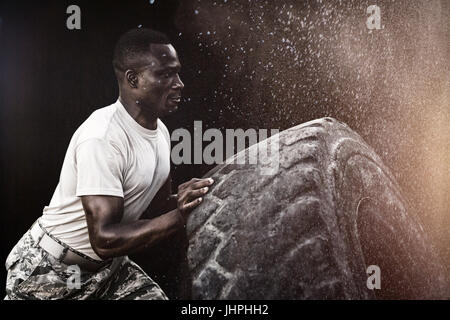 Schwarzem Hintergrund gegen militärische Soldaten trainieren mit Reifen Stockfoto