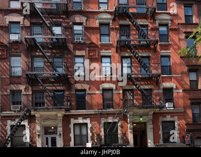 New York, NY USA--12. Juli 2017--der roten Backsteinfassade eines Mehrfamilienhauses mit externen Feuerleitern in New Yorks Greenwich Village. Editor Stockfoto