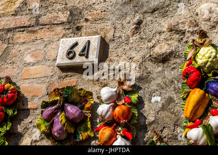 Keramik Anzahl 60 4 64 auf eine Mauer mit Kunststoff Zwiebel, Knoblauch und andere Gemüse Stockfoto