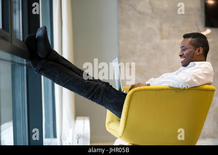 Entspannte schöne afrikanische junger Mann sitzen und meditieren auf Bürostuhl Stockfoto