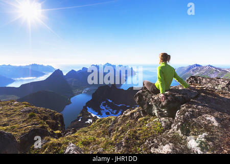 Frau Wanderer entspannen an der Spitze des Berges und mit Blick auf die unglaubliche Aussicht von einem norwegischen Fjord auf der Insel Senja, Nord-Norwegen Stockfoto