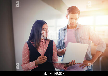 Geschäftskollegen mit Laptop gegen Whiteboard im Tagungsraum Stockfoto