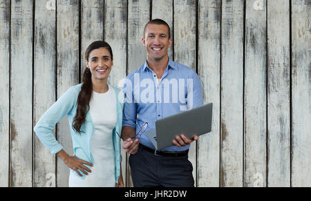 Lächelnde Geschäftsleute mit einem Laptop gegen Holz Hintergrund Stockfoto