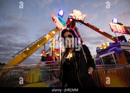 Schöne Frau, die gegen Pendel fährt im Vergnügungspark in der Abenddämmerung Stockfoto