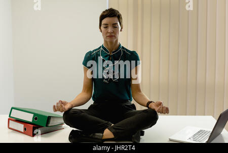 Schöne Geschäftsfrau praktizieren Yoga im Büro Stockfoto