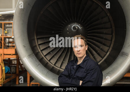 Porträt von männlichen Flugzeugingenieur Wartung stehen mit verschränkten bei Fluggesellschaften Wartungsbetrieb Stockfoto