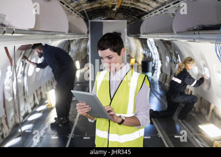 Weibliche Flugzeugingenieur Wartung mit digital-Tablette in ein Flugzeug in Fluggesellschaften Wartungsbetrieb Stockfoto