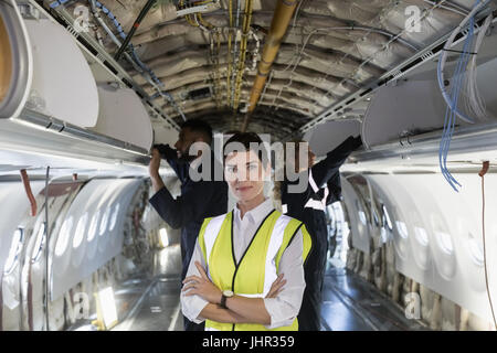 Porträt von weiblichen Flugzeugingenieur Wartung stehen mit verschränkten an Bord eines Flugzeugs an Fluggesellschaften Wartungsbetrieb Stockfoto