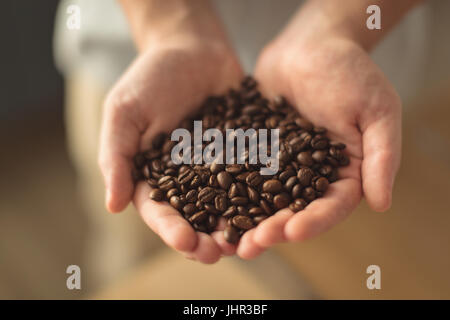 Nahaufnahme von Händen mit gerösteten Kaffeebohnen zu Hause Stockfoto