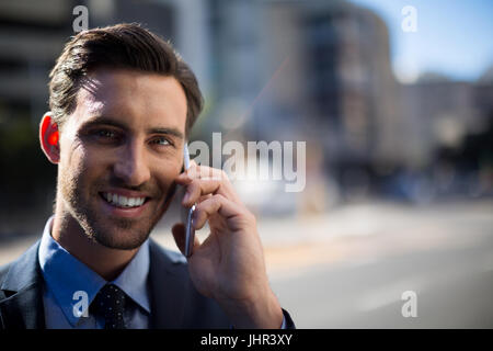 Porträt von lächelnden Geschäftsmann telefonieren mit Handy an einem sonnigen Tag Stockfoto