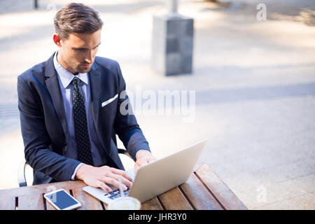 Geschäftsmann mit Laptop am Tisch im Pflaster CafÃƒÂ © Stockfoto