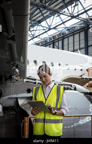 Weibliche Flugzeugingenieur Wartung mit digital-Tablette bei Fluggesellschaften Wartungsbetrieb Stockfoto