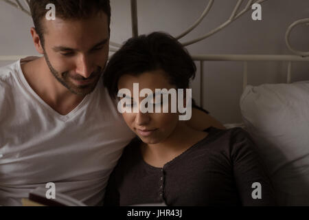 Erhöhte Ansicht des jungen Paares Lesebuch entspannt im Bett zu Hause Stockfoto