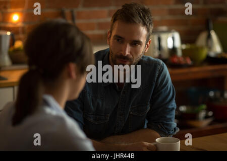 Mann im Gespräch mit Frau beim Kaffeetrinken am Tisch in der Küche Stockfoto