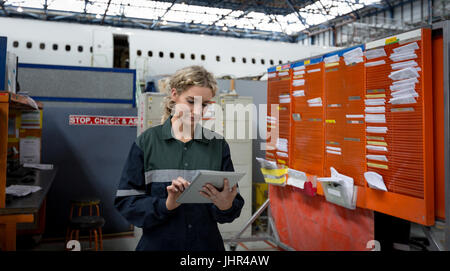 Weibliche Flugzeugingenieur Wartung mit digital-Tablette bei Fluggesellschaften Wartungsbetrieb Stockfoto