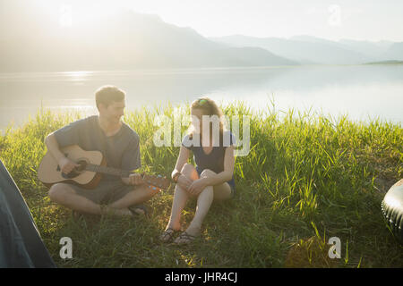 Romantische Mann spielt Gitarre für seine Frau auf Campingplatz Stockfoto