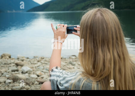 Rückansicht des Frau fotografieren See von Handy Stockfoto