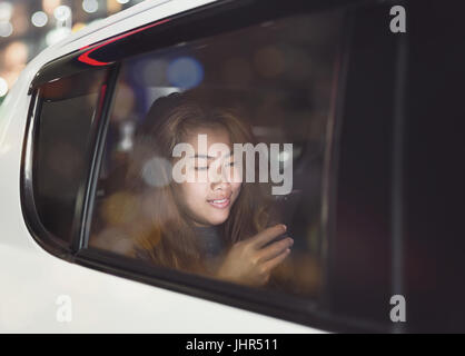 Frau mit Telefon im Auto in der Stadt am Abend Stockfoto