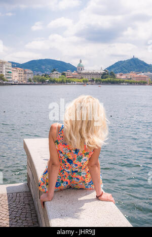 Attraktive junge Blondine am Ufer mit Blick auf den Comer See, Italien Stockfoto