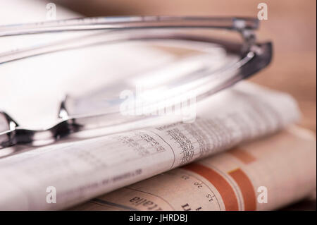 Brille liegen auf einem Stapel Zeitungen Stockfoto